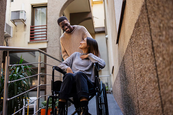 A man pushing a woman in a wheelchair outside