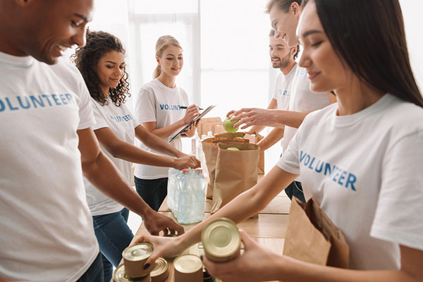 Adult volunteers putting canned goods in paper bags